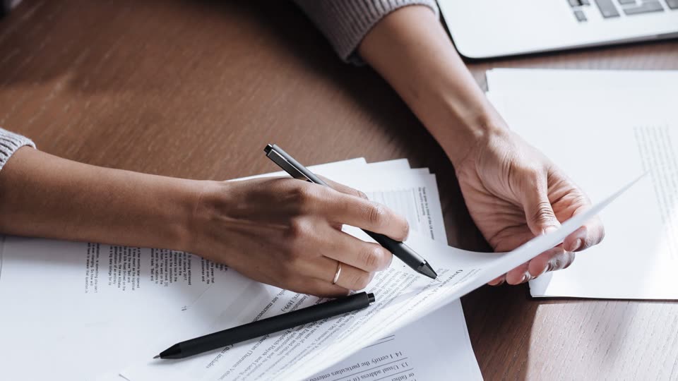 Mãos assinando documentos sobre a mesa